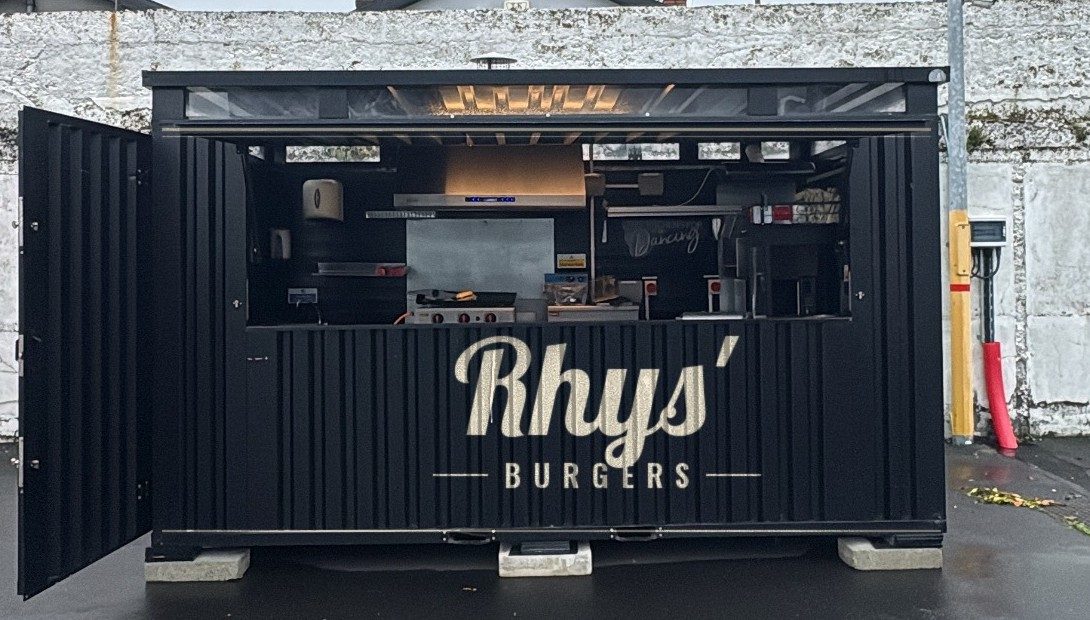 Black Rhys' Burgers food unit with cream script lettering, serving hatch open